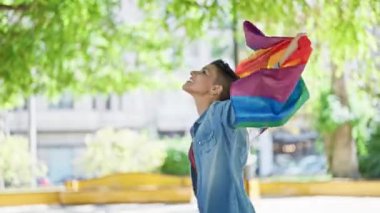 Genç, güzel İspanyol kadın gülümsüyor. Elinde gökkuşağı bayrağı var. Parkta kendi kendine dönüyor.