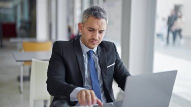 Genç İspanyol iş adamı ofiste dizüstü bilgisayar kullanıyor.