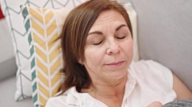 Orta yaşlı İspanyol kadın kanepede yatıp evde uyuyor.