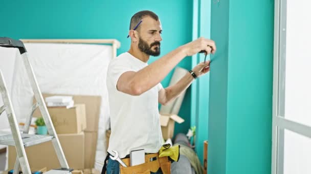 Young Hispanic Man Repairman Measuring Wall Taking Notes New Home — Stock Video