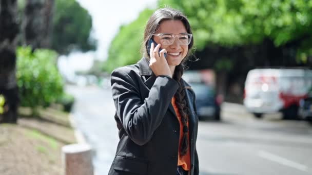 若い美しいヒスパニック系の女性のビジネスワーカーが路上でタクシーを求めるスマートフォンで話しています — ストック動画