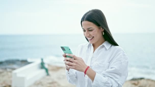 Jovem Bela Mulher Hispânica Usando Smartphone Sorrindo Beira Mar — Vídeo de Stock