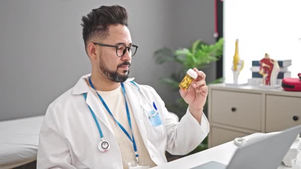 Ung Latinamerikansk Man Läkare Med Hjälp Laptop Innehav Piller Kliniken — Stockvideo