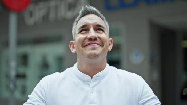 Joven Hombre Hispano Sonriendo Confiado Mirando Cielo Con Gesto Ganador — Vídeo de stock