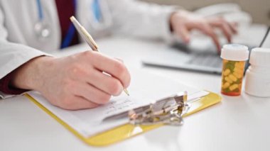 Genç İspanyol doktor panoya yazı yazıyor. Klinikte dizüstü bilgisayar kullanıyor.