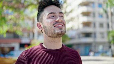 Parkta kendinden emin gülümseyen İspanyol genç adam.