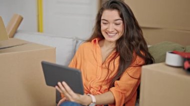 Genç, güzel İspanyol bir kadın yeni evindeki kanepede otururken görüntülü konuşma yapıyor.