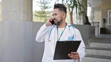 Genç latin doktor, hastanede akıllı telefondan tıbbi raporları okuyor.