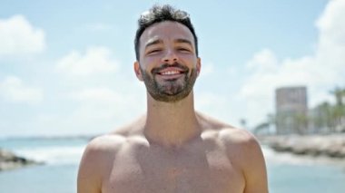 Genç İspanyol turist kumsalda kendinden emin bir şekilde gülümsüyor.