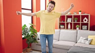 Genç İspanyol adam evde dans dinlerken kendinden emin bir şekilde gülümsüyor.