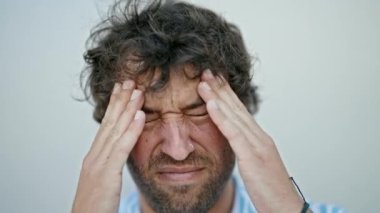 Genç İspanyol adam izole edilmiş beyaz arka plan yüzünden baş ağrısı çekiyor.