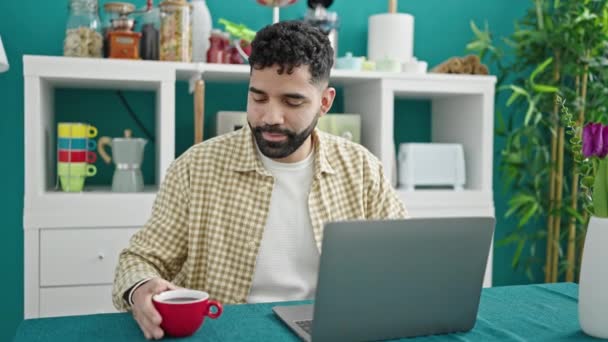 Ung Hispanic Mann Som Bruker Laptop Drikke Kaffe Middagsrommet – stockvideo