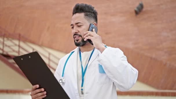 Jovem Latino Homem Médico Falando Smartphone Leitura Relatório Médico Hospital — Vídeo de Stock