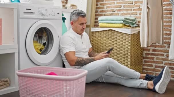 Çamaşır Odasında Çamaşır Makinesi Bekleyen Akıllı Telefon Kullanan Genç Bir — Stok video
