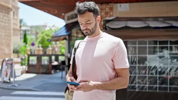 Joven Hombre Hispano Usando Smartphone Con Mochila Terraza Cafetería — Vídeo de stock