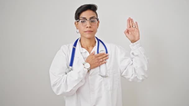年轻美丽的惊慌失措的女医生 手托着胸膛 在与世隔绝的白色背景下宣誓 — 图库视频影像