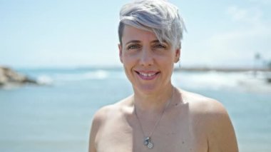 Plajda gülümseyen bikini giyen genç bir kadın turist.