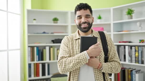 Jovem Estudante Hispânico Sorrindo Livro Segurando Confiante Universidade Biblioteca — Vídeo de Stock