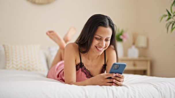 年轻美丽的惊慌失措的女人用智能手机躺在卧室的床上 — 图库视频影像