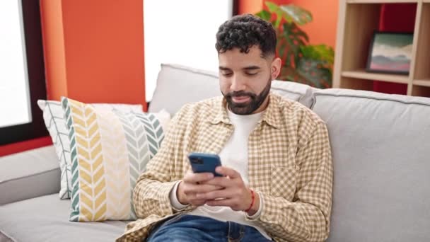 Hombre Hispano Joven Usando Teléfono Inteligente Sentado Sofá — Vídeos de Stock