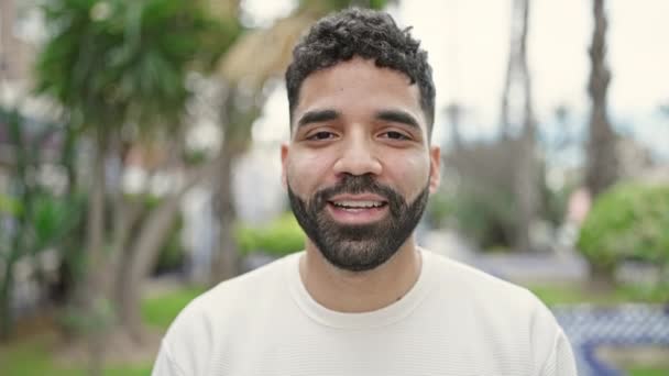 Ung Latinamerikansk Man Ler Tryggt Talar Parken — Stockvideo