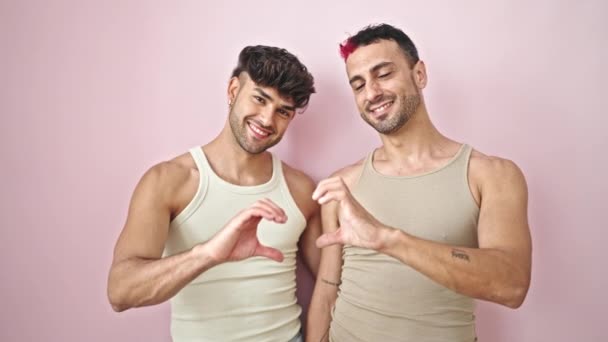 二人の男カップル抱擁お互いに行いハートジェスチャー上の隔離されたピンクの背景 — ストック動画