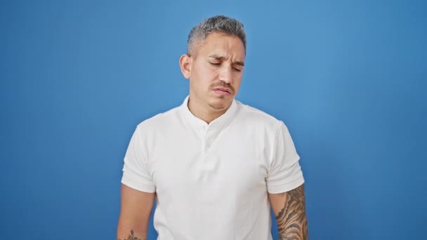 Mladý Hispánec Muž Hledá Hodinky Vážným Výrazem Přes Izolované Modré — Stock video