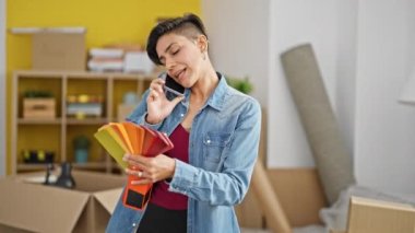 Genç ve güzel İspanyol kadın renk testi seçiyor. Yeni evinde akıllı telefondan konuşuyor.