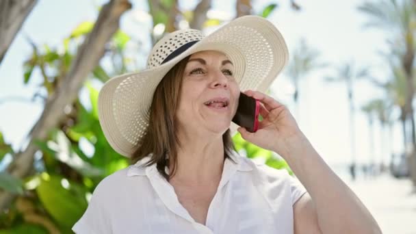 在公园里戴着夏帽的中年惊慌失措的女人用智能手机聊天 — 图库视频影像