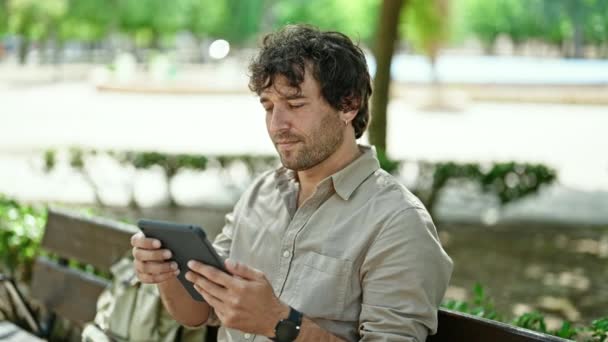 Jovem Hispânico Usando Touchpad Sentado Banco Sorrindo Parque — Vídeo de Stock