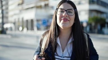 Sırt çantalı genç İspanyol kadın turist sokakta gülümsüyor.