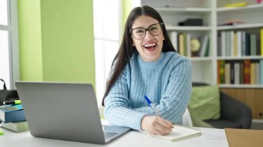 Kütüphanede bilgisayar kullanan genç İspanyol kız öğrenci.