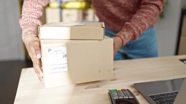 Afro-amerikan bir iş adamı elinde paketlerle ofise gülümsüyor.