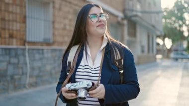 Sırt çantalı genç İspanyol kadın turist sokakta kamerayla fotoğraf çekiyor.