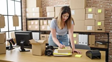 Genç sarışın kadın ecommerce iş işçisi anımsatıcı kağıt ambalaj profesyonel kamera ofis