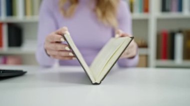 Genç, güzel İspanyol kadın kütüphanede kitap açıyor.