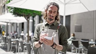 Genç İspanyol garson gülümseyerek kahve dükkanının terasında notlar alıyor.