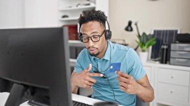 Ofisteki kredi kartını kullanarak kulaklık takan Afrikalı Amerikalı bir iş adamı.