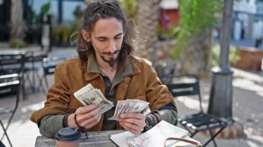 Genç İspanyol turist kahve dükkanının terasında oturmuş dolar sayıyor.