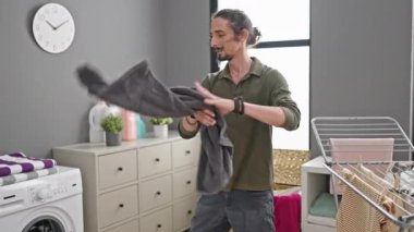 Çamaşır odasında çamaşır makinesine çamaşır atan genç bir İspanyol.
