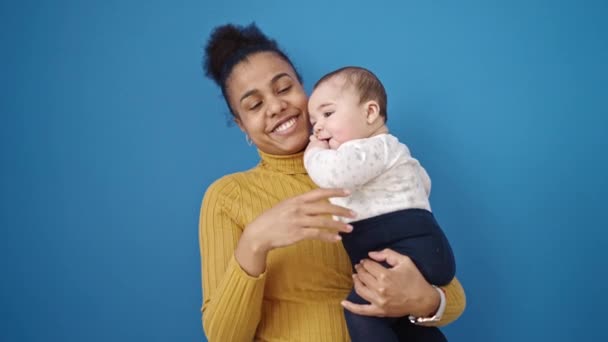 母と息子は自信を持って笑顔で赤ちゃんを指して隔離された青の背景 — ストック動画