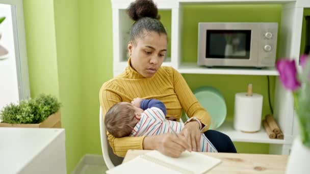 食事室で母乳育児中の母親と息子のメモを書く — ストック動画