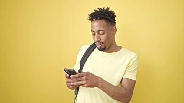 Afrika Amerika Pria Mengenakan Ransel Menggunakan Smartphone Atas Terisolasi Kuning — Stok Video