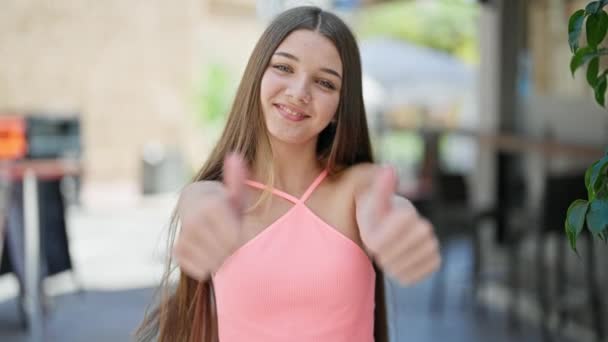 年轻美丽的姑娘笑着自信地在咖啡店的阳台上竖起大拇指签个名 — 图库视频影像