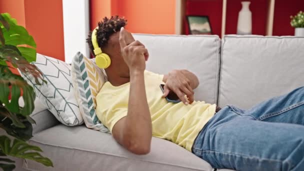 アフリカ系アメリカ人の男は家でソファで音楽を聴いて — ストック動画