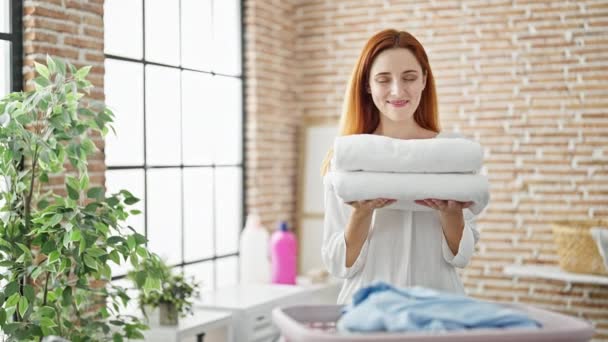 Młoda Ruda Kobieta Uśmiecha Się Pewnie Trzymając Złożone Ręczniki Pralni — Wideo stockowe
