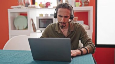 Yemek odasındaki masada oturan Latin asıllı genç bir adam.