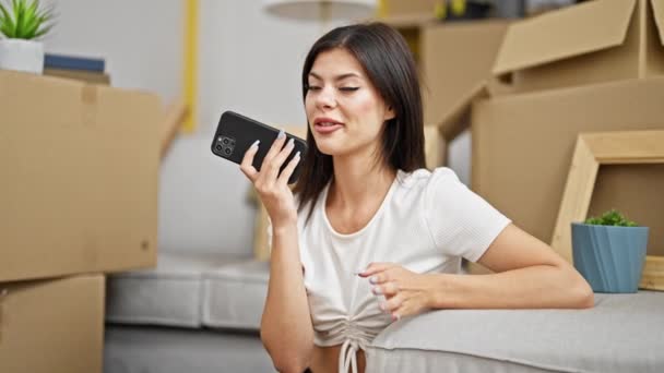 若い白人女性が新しい家で床に座ってスマートフォンで音声メッセージを送信 — ストック動画