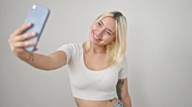 Dolarları tutan genç, güzel İspanyol bir kadın izole edilmiş beyaz arka planda akıllı telefondan selfie çekiyor.