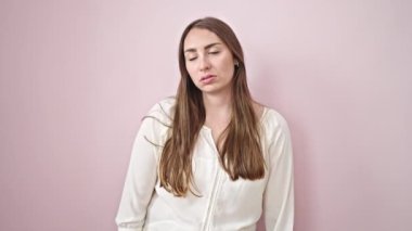 Sıkıcı suratı olan, soyutlanmış pembe arka planda duran genç, güzel İspanyol bir kadın.